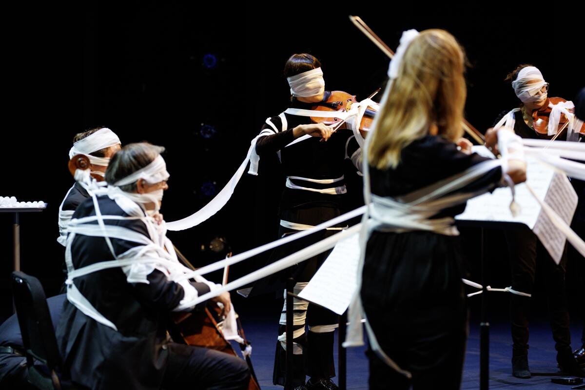 Members of the L.A. Chamber Orchestra covered in gauze while performing Yoko Ono's "Sky Piece to Jesus Christ"
