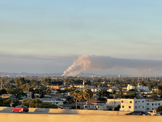 A huge white plume of smoke rising out of an urban area.