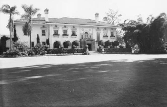 A black and white image of a large estate home and sprawling lawn. 