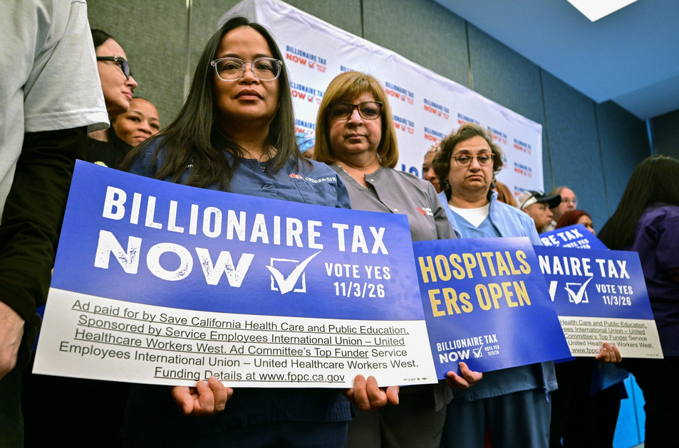 People wearing medical scrubs hold signs supporting a "Billionaire Tax" to keep hospitals and emergency rooms open, urging a vote on 11/3/26.