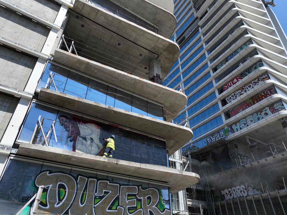 Contractors begin power washing and removing graffiti off the Oceanwide Plaza.