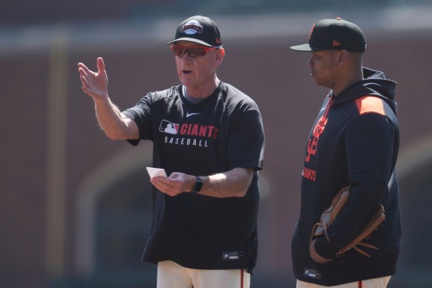 San Francisco Giants third base coach Matt Williams, left, talks with Rafael Devers before a baseball game between the Giants and the Cleveland Guardians in San Francisco, Thursday, June 19, 2025. (AP Photo/Jeff Chiu)