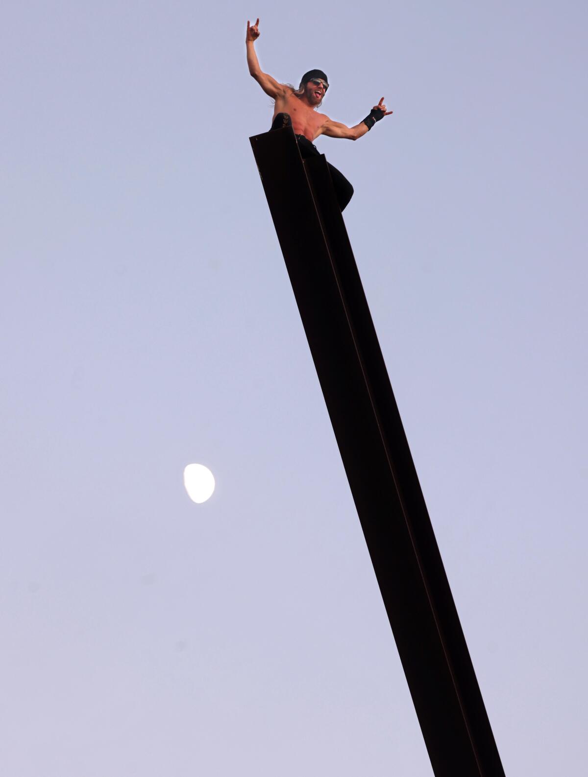 Stuntman Kane Safari, a.k.a. The Parkour Jesus, enjoys the cool air up high after scaling the sculpture in Venice Beach. 