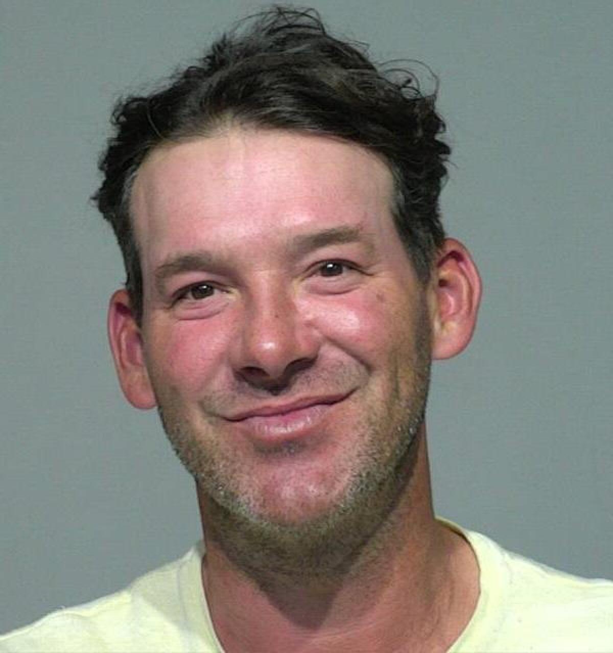 A man smiles for a booking photo.