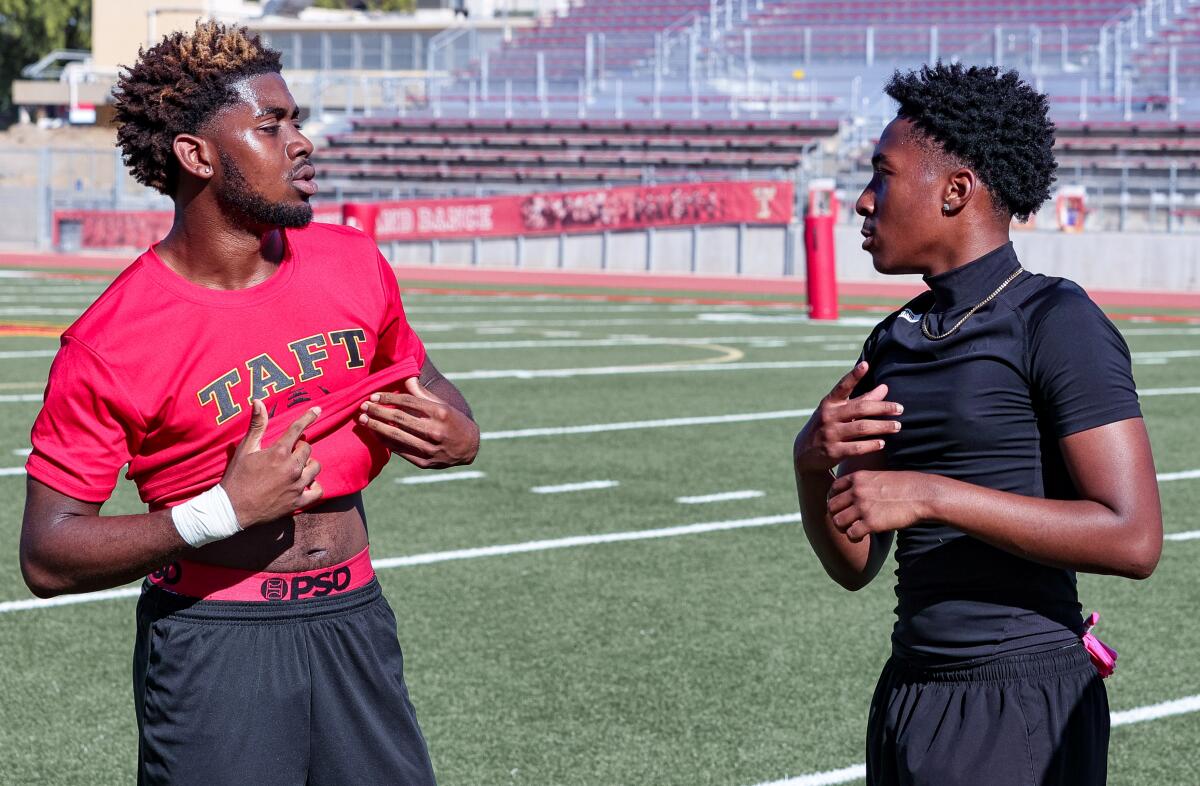 Taft football players Carter Wallace, left, and McCardell Barton communicate with sign language during practice.