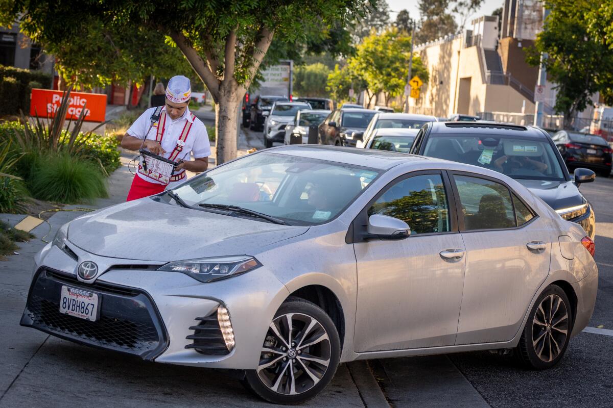 A drive-thru worker works the long lines at the In-N-Out Burger in the 9000 block of Venice Blvd. in Los Angeles.