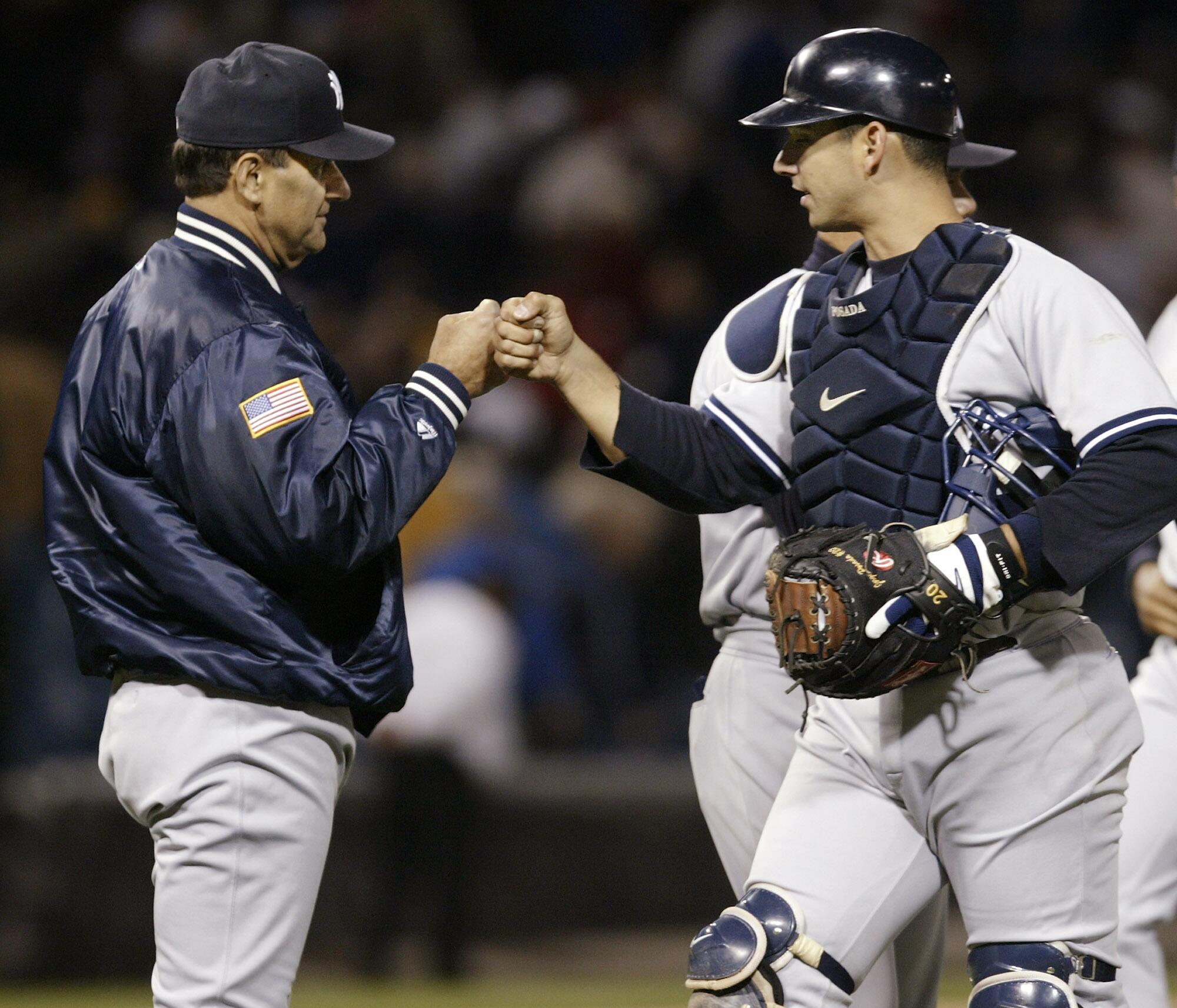 Yankees manager Joe Torre bumps fists with catcher Jorge Posada after a win in April 2004.