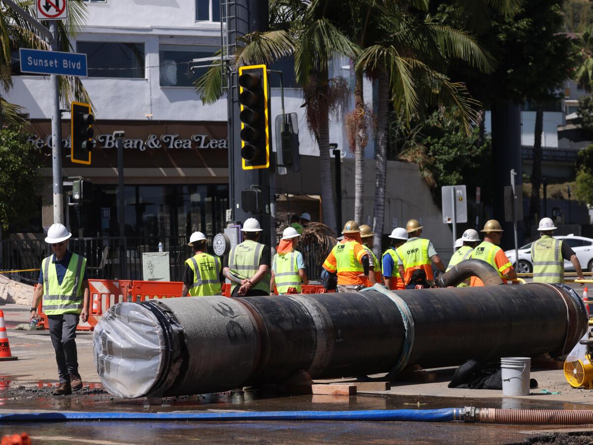 DWP workers stand next to the new pipe that will replace the damaged pipe.