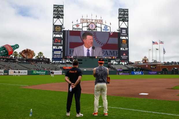 San Francisco Giants vice president of medical and performance Dave Groeschner and San Francisco Giants' Matt Chapman (26) stop to watch former San Francisco Giants player Jeff Kent be inducted into the Baseball Hall of Fame before their MLB game at Oracle Park in San Francisco, Calif., on Sunday, July 26, 2026. (Jose Carlos Fajardo/Bay Area News Group)
