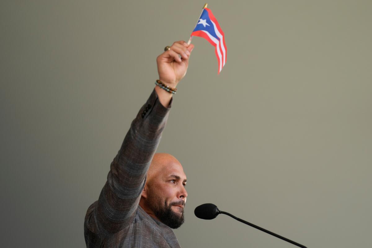 Carlos Beltrán waves a Puerto Rican flag while speaking during the Baseball Hall of Fame induction ceremony.