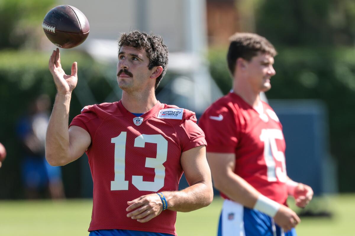 Rams quarterback Stetson Bennett, left, twirls a football in front of quarterback Ty Simpson at training camp on Sunday.