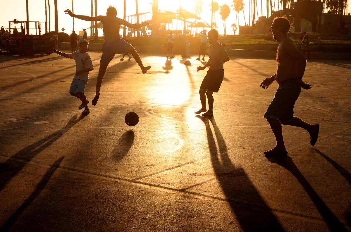 People play basketball as the sun sinks low in the sky.