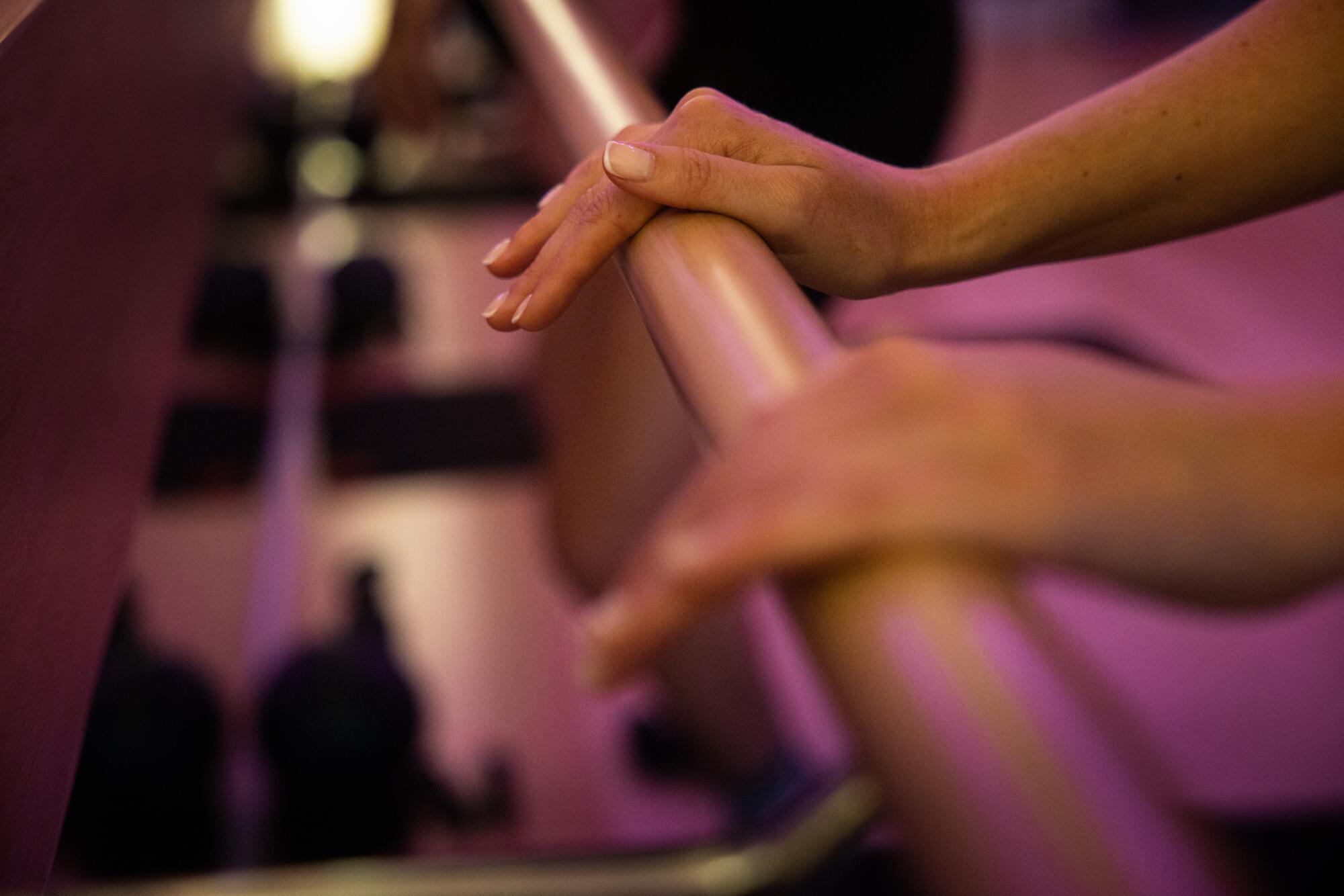 A ballet barre is used for postural support and balance during the workout.