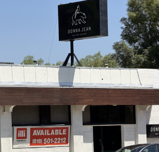 The exterior of a white one story building has a black sign on top which says Donna Jean. Below there is a red and white sign which says AVAILABLE and a phone number.