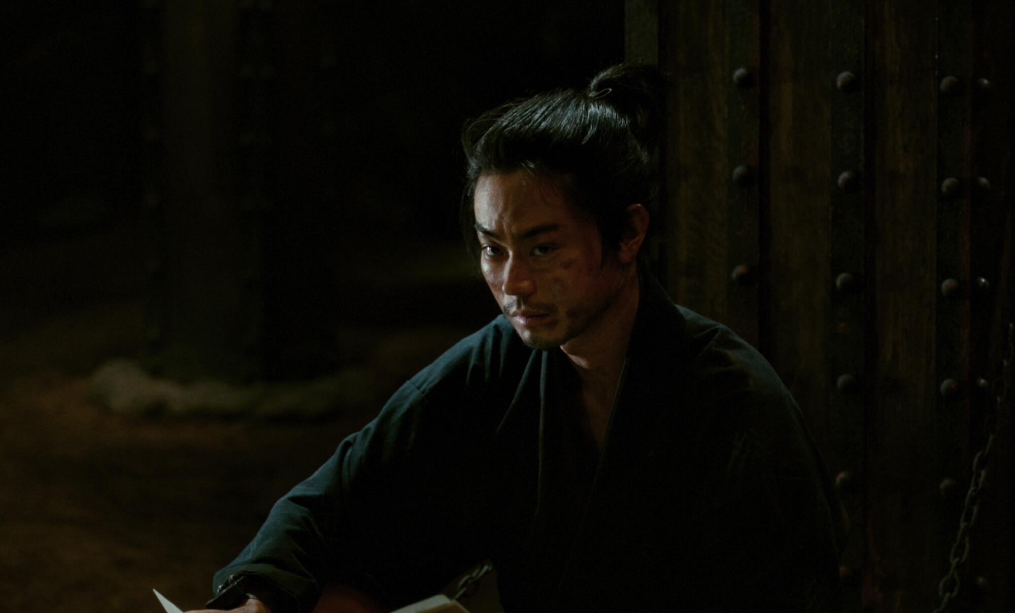 A man sits chained in a cellar.