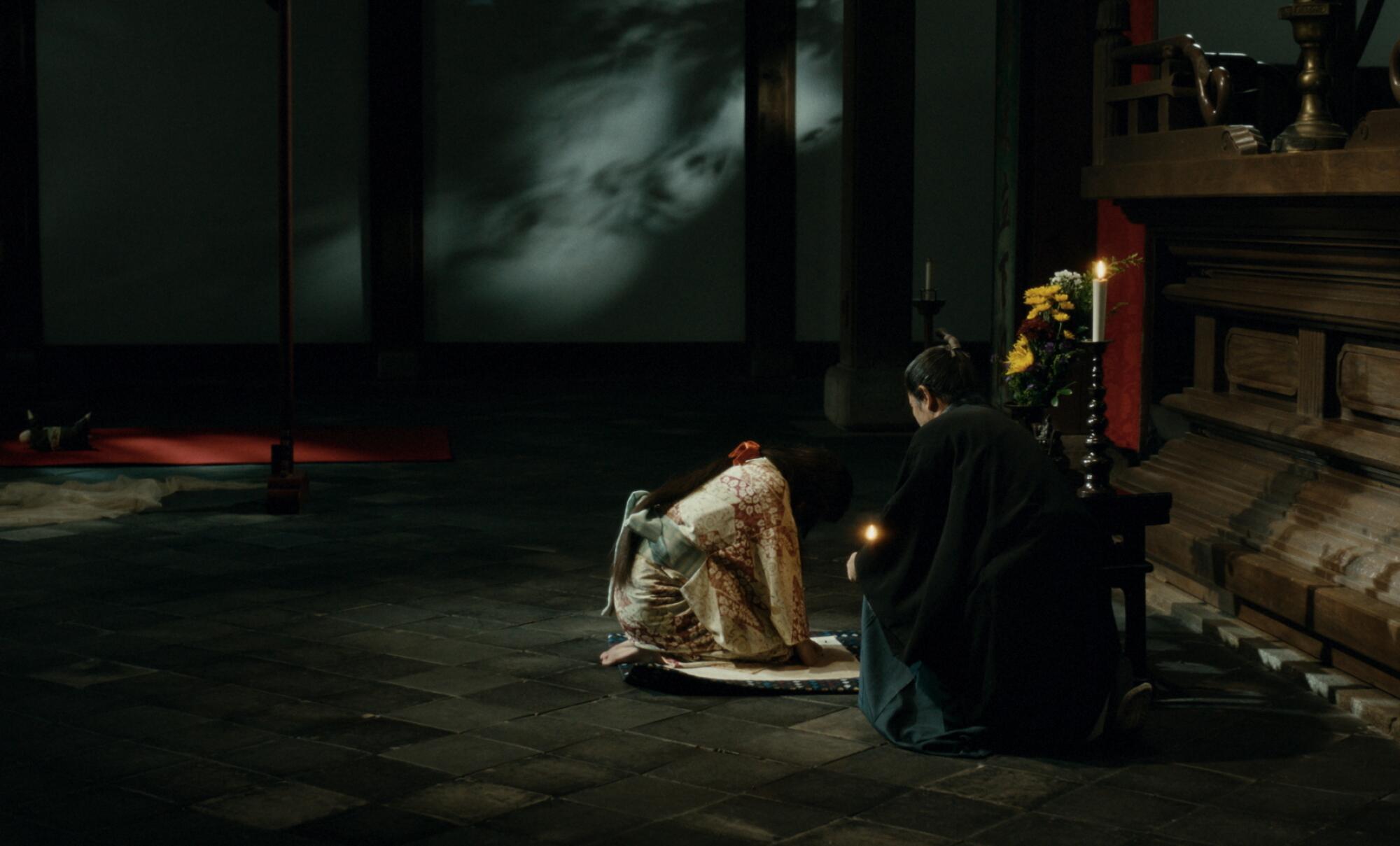 A woman kneels before her husband in feudal Japan.