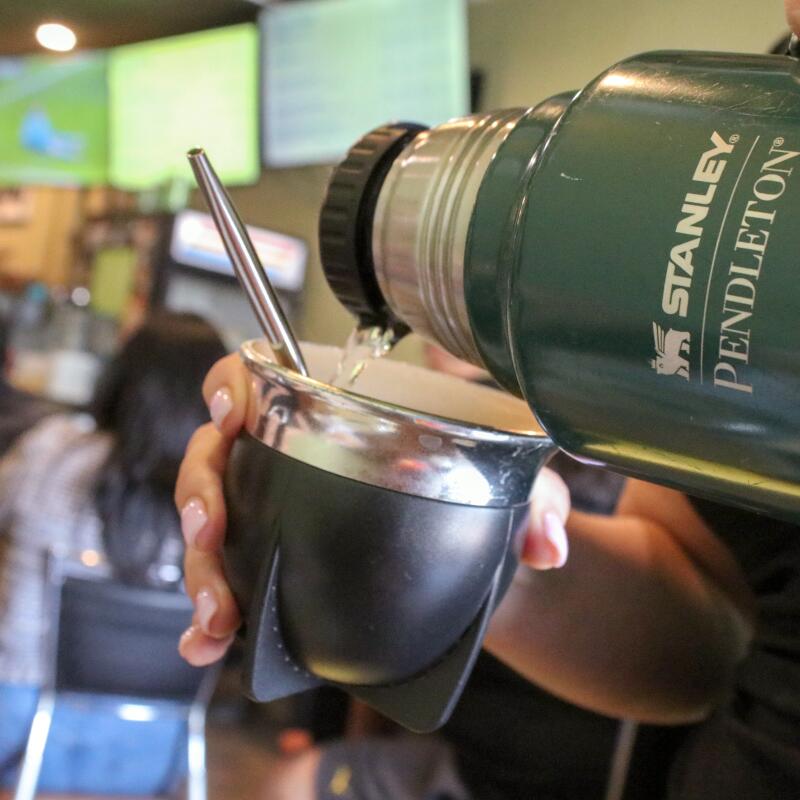 Gabriela Simoni, owner of cafe Mate Conmigo, pours hot water into a customer's gourd at Mate Conmigo.