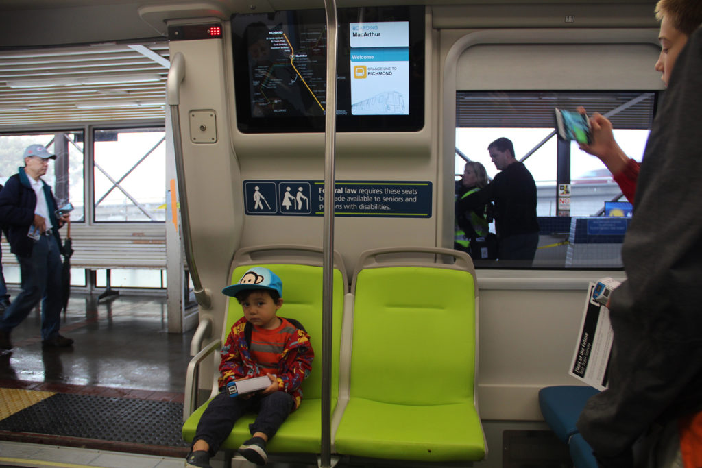A youngster sits in one of BART's new cars Sunday at MacArthur Station during its open house event. The cars come equipped with electronic maps and brightly colored seating, among other features.