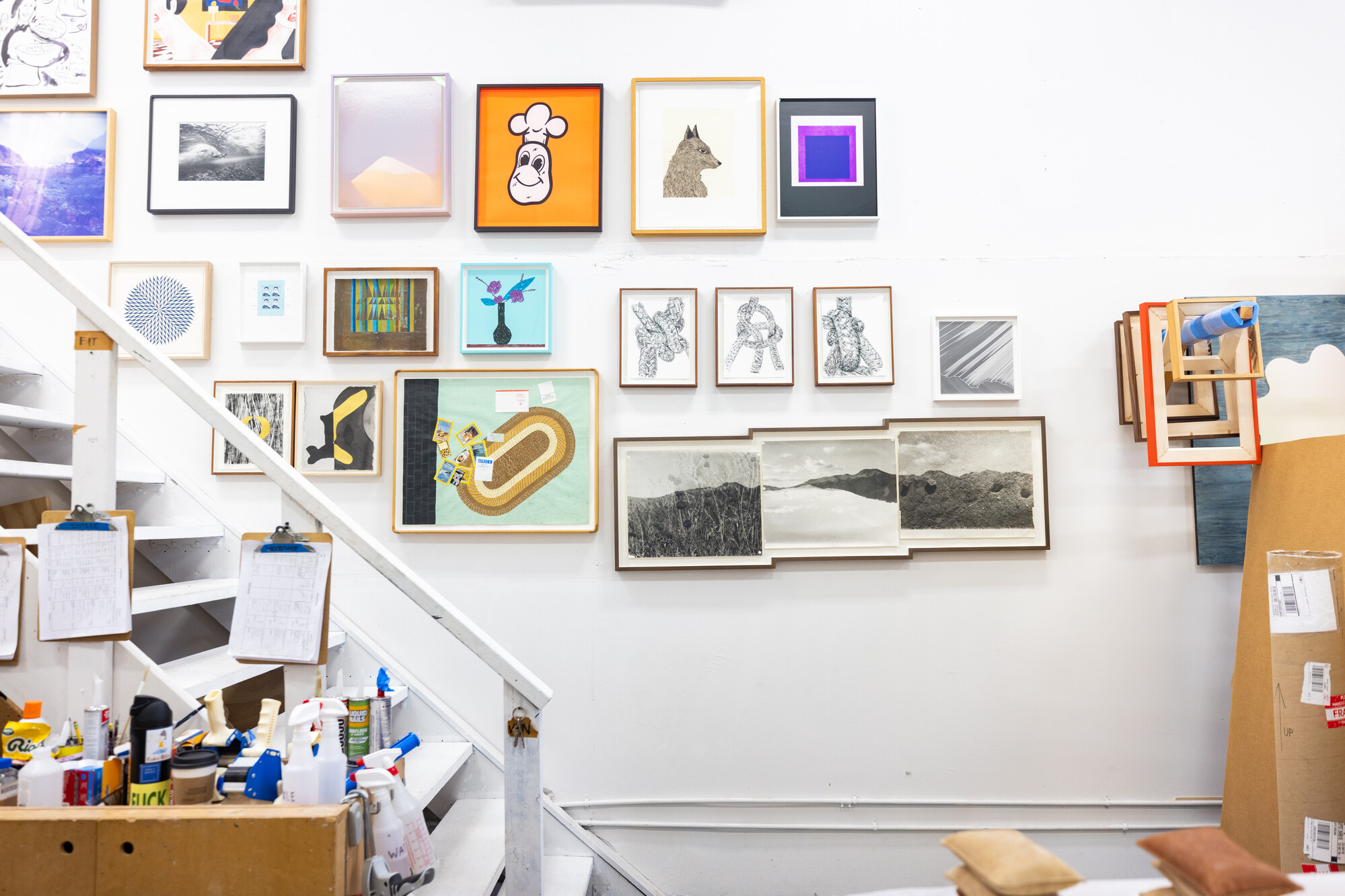 salon-style wall hung with colorful artwork above staircase to gallery