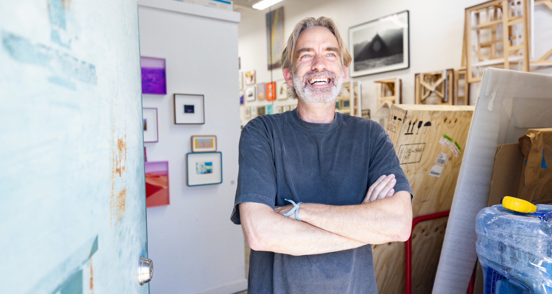 white man with gray hair smiles with arms crossed