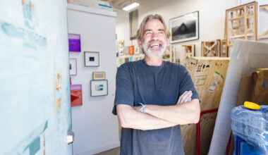 white man with gray hair smiles with arms crossed
