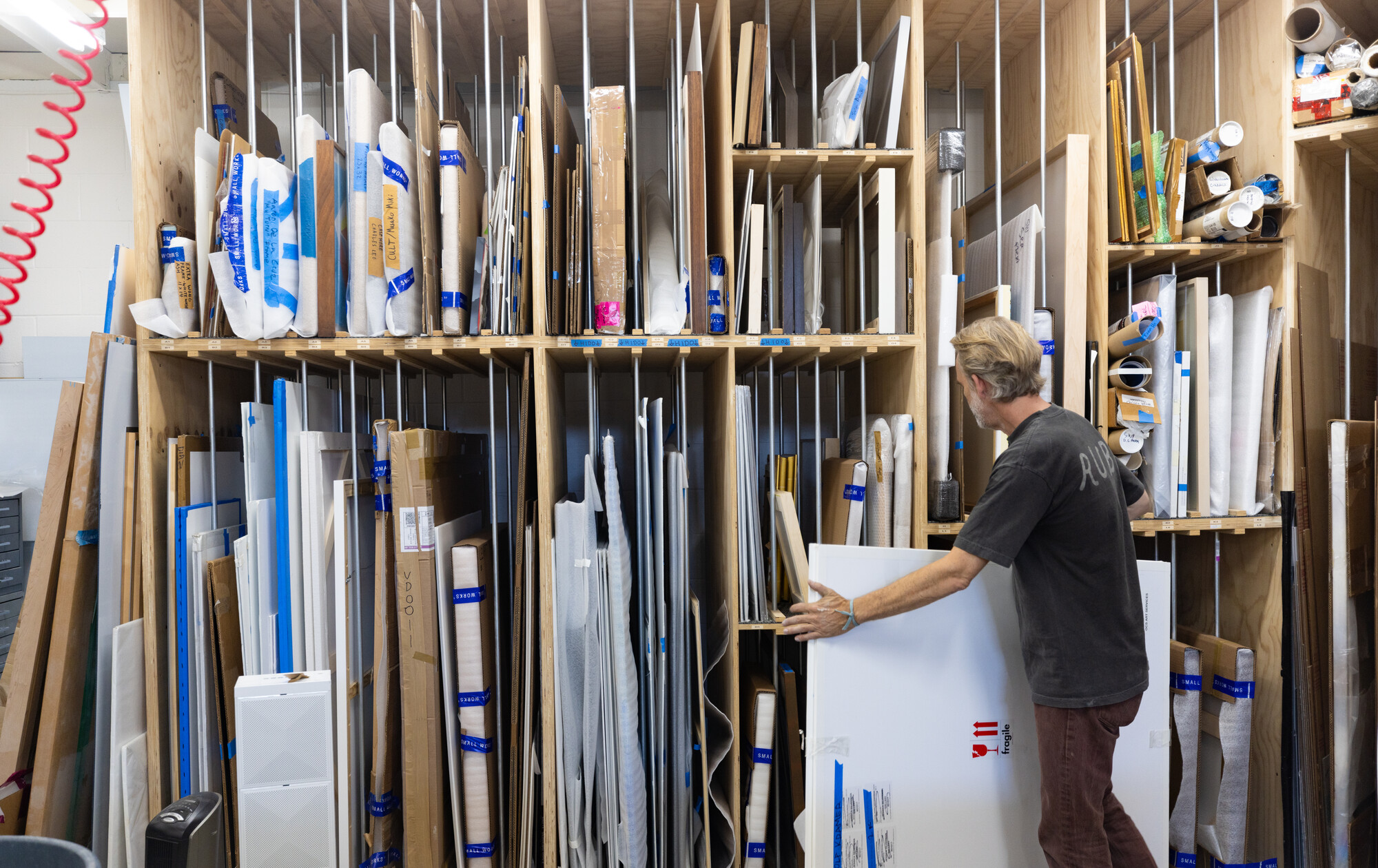 man carries art in front of storage racks
