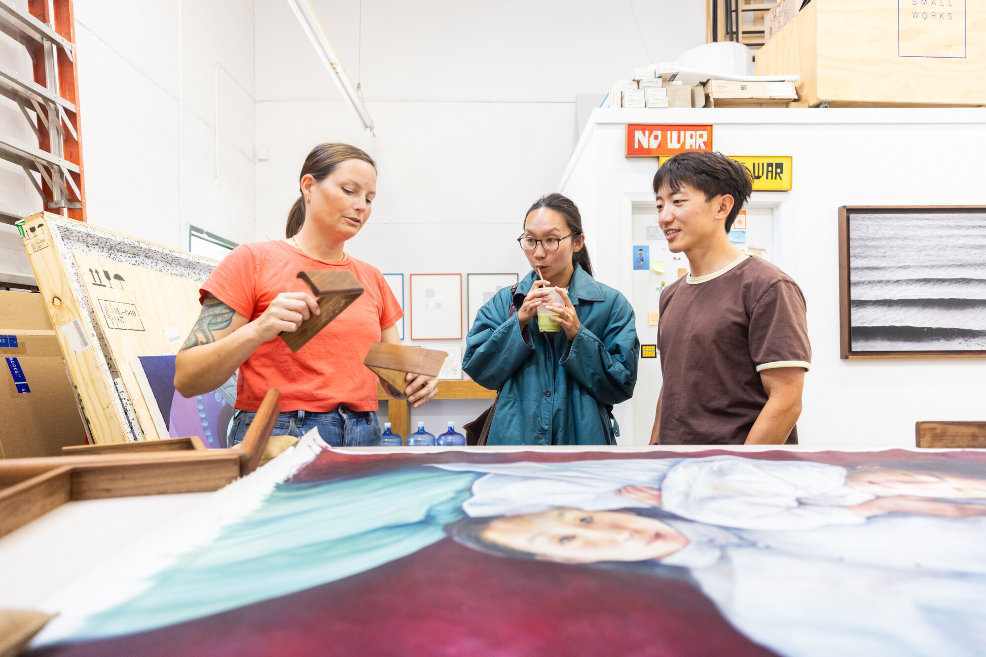 three people talk over spread-out art