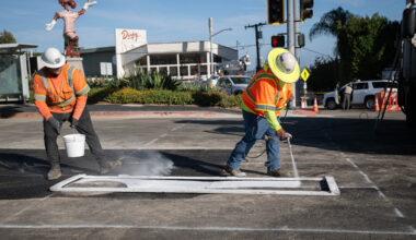 2 LADWP workers in safety gear stripe the pavement in West Hollywood.