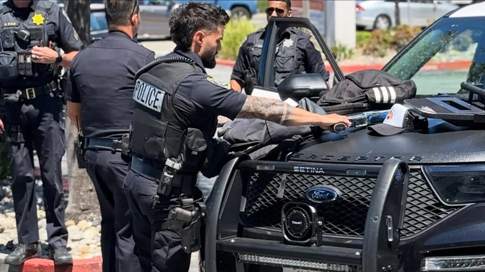 Police officer searching through items on the hood of a police vehicle.