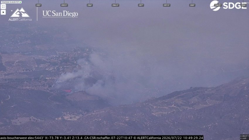 Aerial view of smoke from a brush fire in a remote, hilly area.