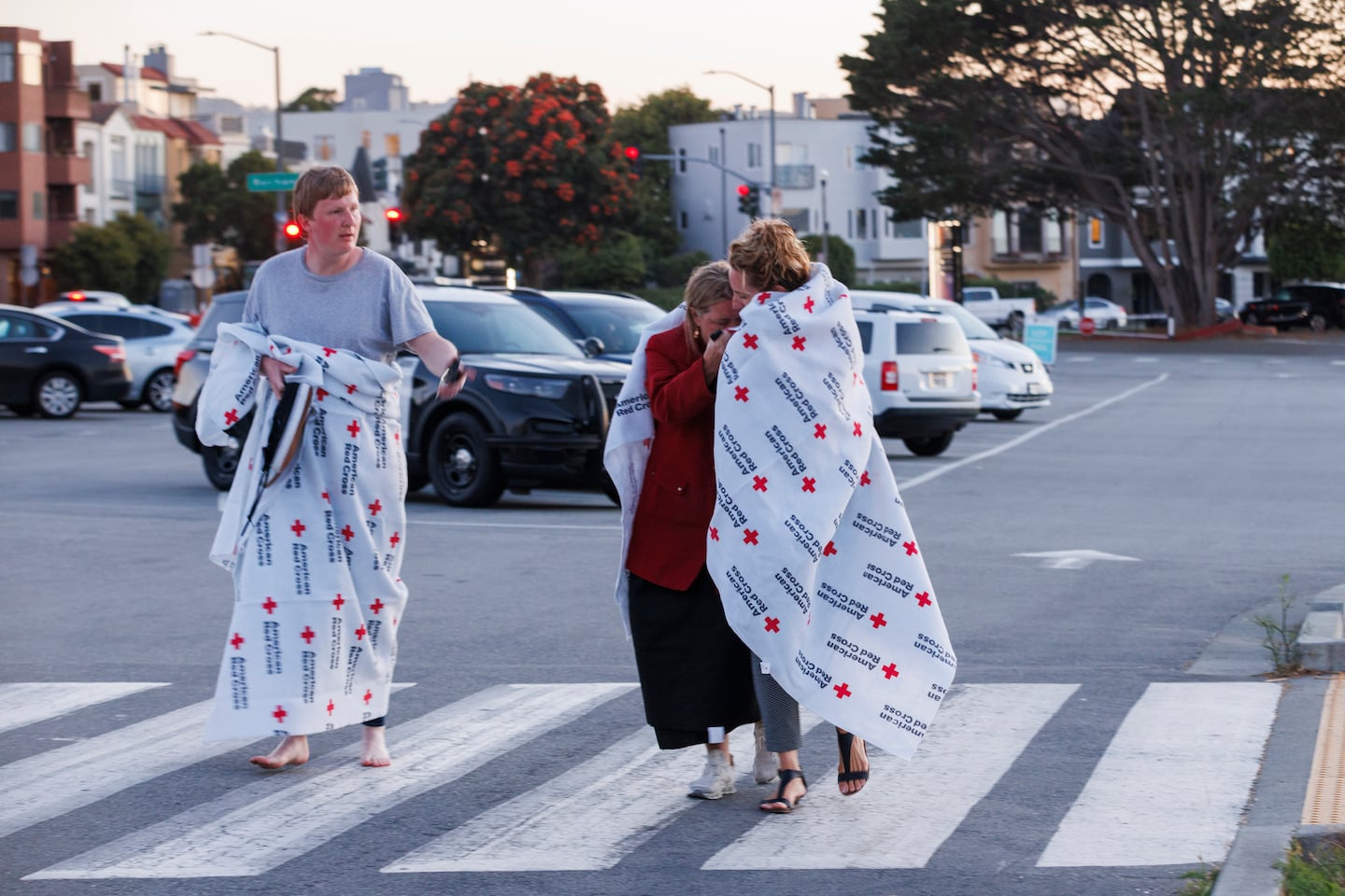 People cover themselves with American Red Cross blankets at Fort Mason, where the Red Cross has set up an assistance center for people impacted by a boat incident.
