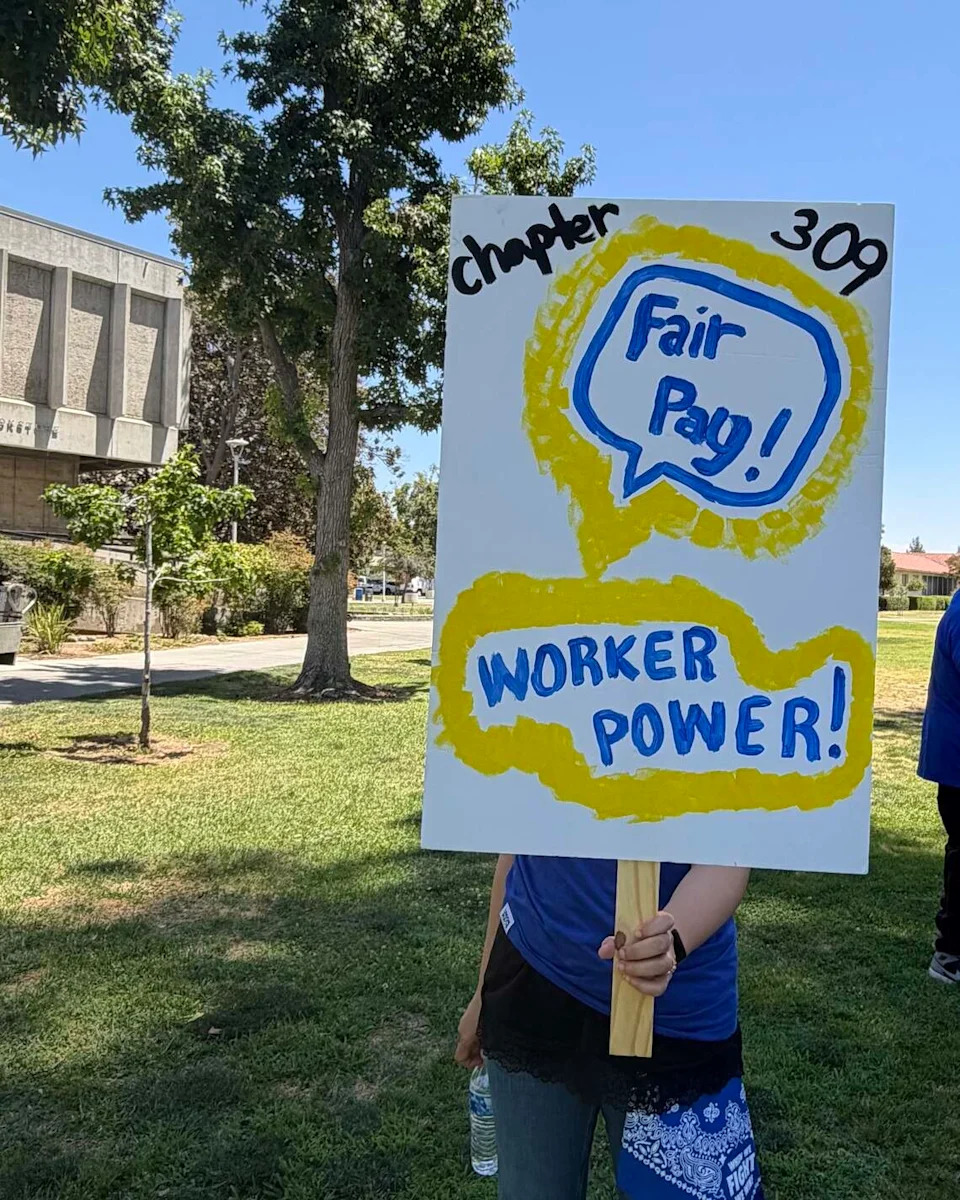 A member of the union poses with their sign covering their face.