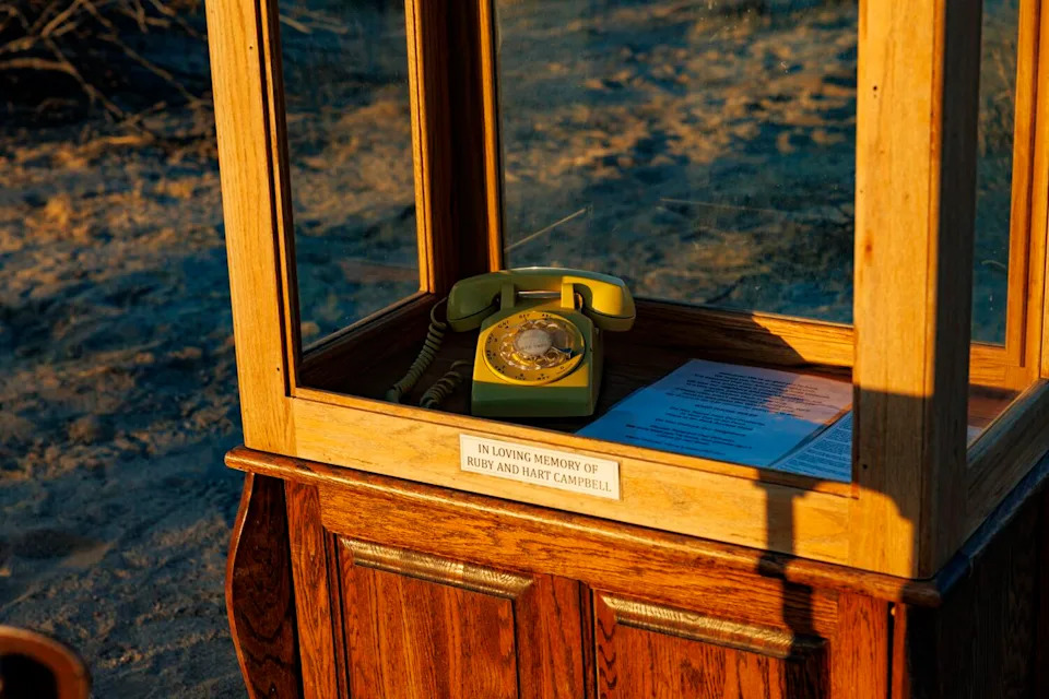 An old rotary telephone sits inside a custom phone booth.