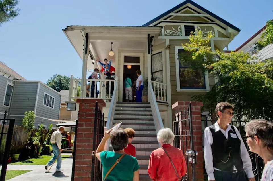 A stream of people tour Dorothea Puente’s former home on Sept. 15, 2013. In 1988, seven victims were found buried in the yard at left. Puente was convicted on three counts of first-degree murder in 1993.