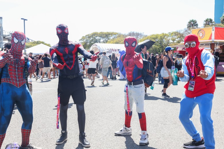 Four people in various spider man costumes