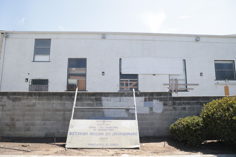 A white building with a fallen sign 