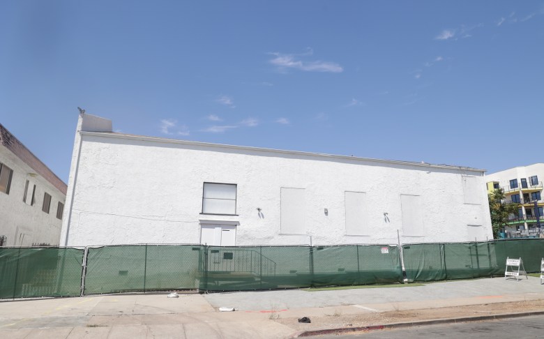 The side of a white building behind construction fence