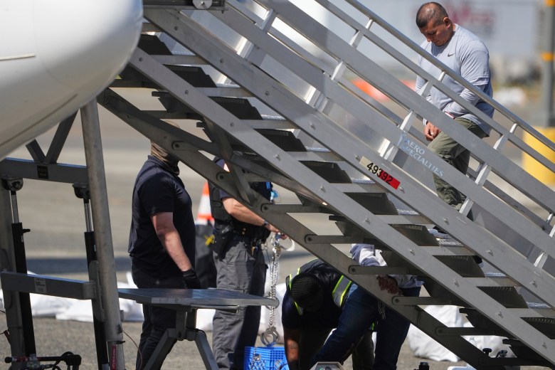 Aluminum staircase at an airport with people around and ascending.