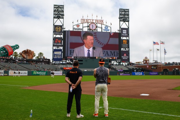 San Francisco Giants vice president of medical and performance Dave Groeschner and San Francisco Giants' Matt Chapman (26) stop to watch former San Francisco Giants player Jeff Kent be inducted into the Baseball Hall of Fame before their MLB game at Oracle Park in San Francisco, Calif., on Sunday, July 26, 2026. (Jose Carlos Fajardo/Bay Area News Group)