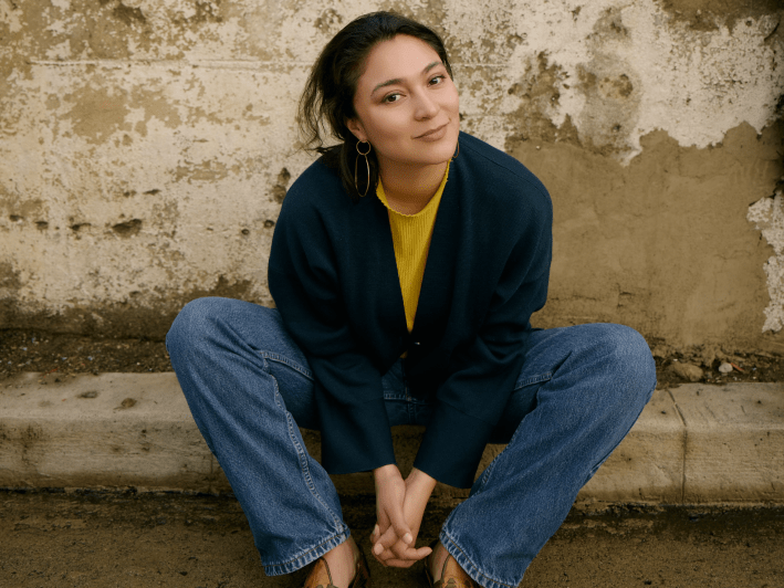 a woman sits on the sidewalk in jeans