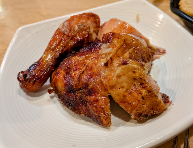 Three pieces of roasted chicken, including a drumstick and two breast portions, served on a white plate.