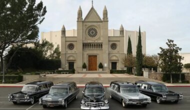 small fleet of Cadillac hearses displayed in front of large cathedral