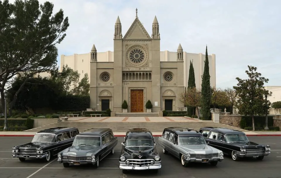small fleet of Cadillac hearses displayed in front of large cathedral