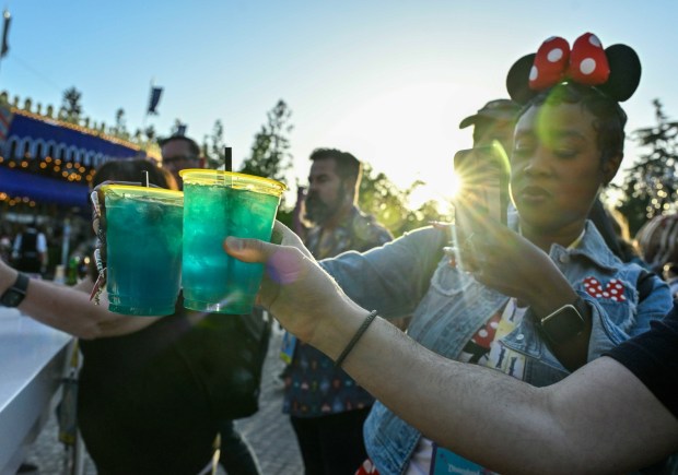 Sharronda Williams and Andrew Freund take pictures of the new Celebration Cocktail - tequila, rum, vodka and glittery blue raspberry lemonade, topped with sprite and garnished with a cherry - during a media preview of Disneyland 70th anniversary celebration in Anaheim, CA, on Wednesday, May 14, 2025. Disneyland is celebrating its 70th anniversary from May 16, 2025 through summer 2026.(Photo by Jeff Gritchen/MediaNews Group/Orange County Register via Getty Images)