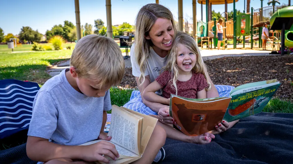 kids and their mom reading in a park