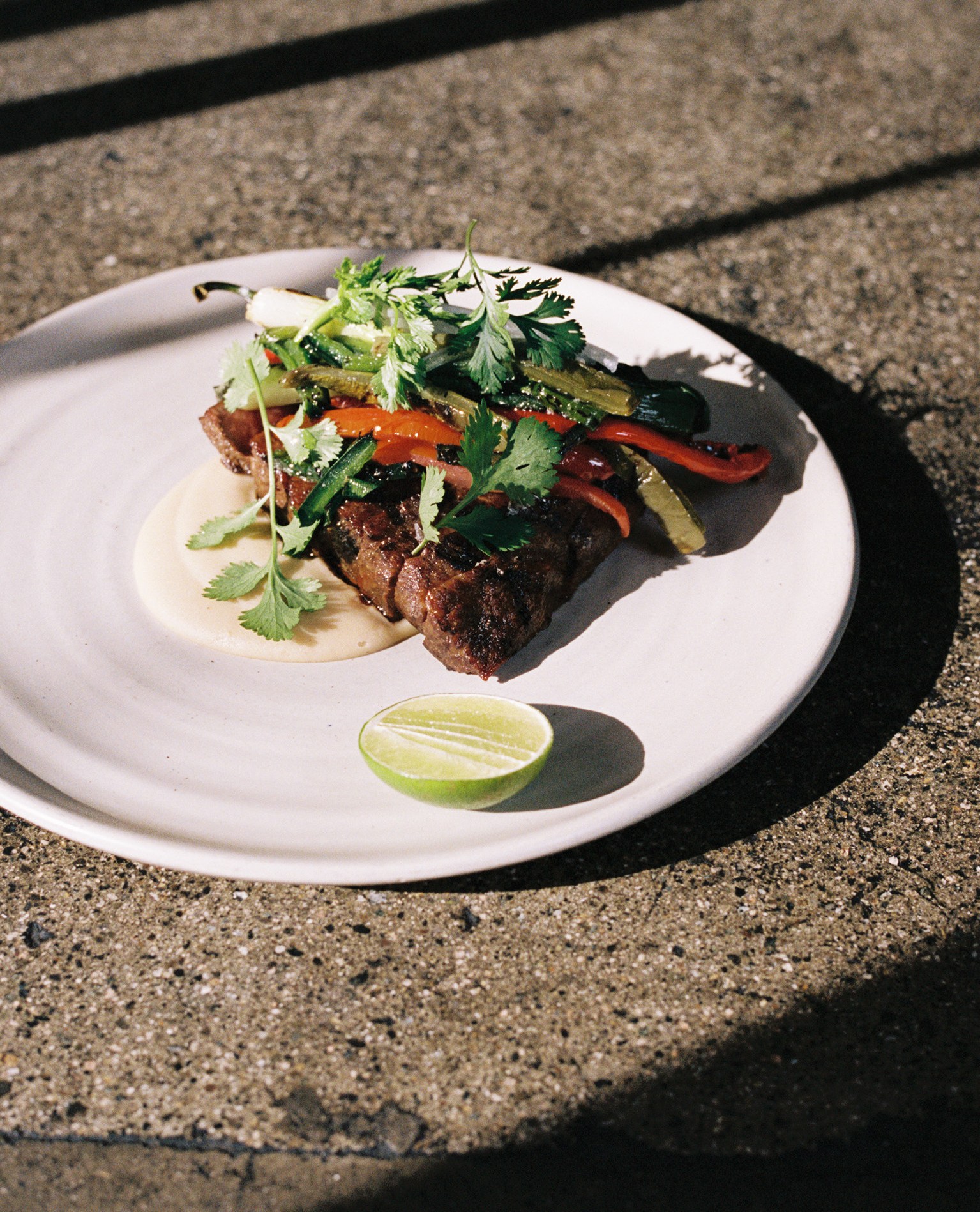 Carne asada on a white plate with a lime at Damian.