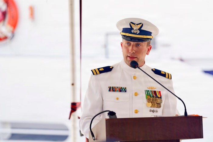 A person in U.S. Coast Guard uniform speaks at a podium.