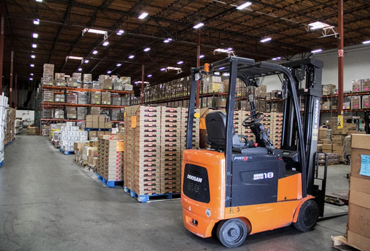 Orange forklift in warehouse of industrial shelves