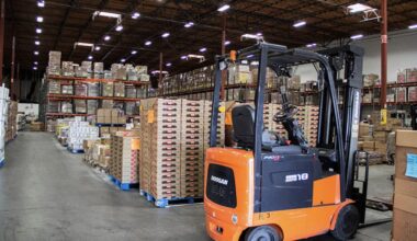 Orange forklift in warehouse of industrial shelves