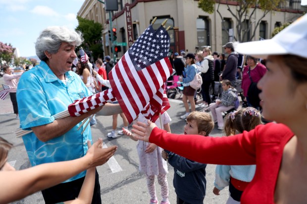 Knights of Columbus member Nabor Andrew Baca, left, hands out flags to spectators as the Alameda 4th of July Parade heads down Park Street in Alameda, Calif., on Saturday, July 4, 2026. (Jane Tyska/Bay Area News Group)
